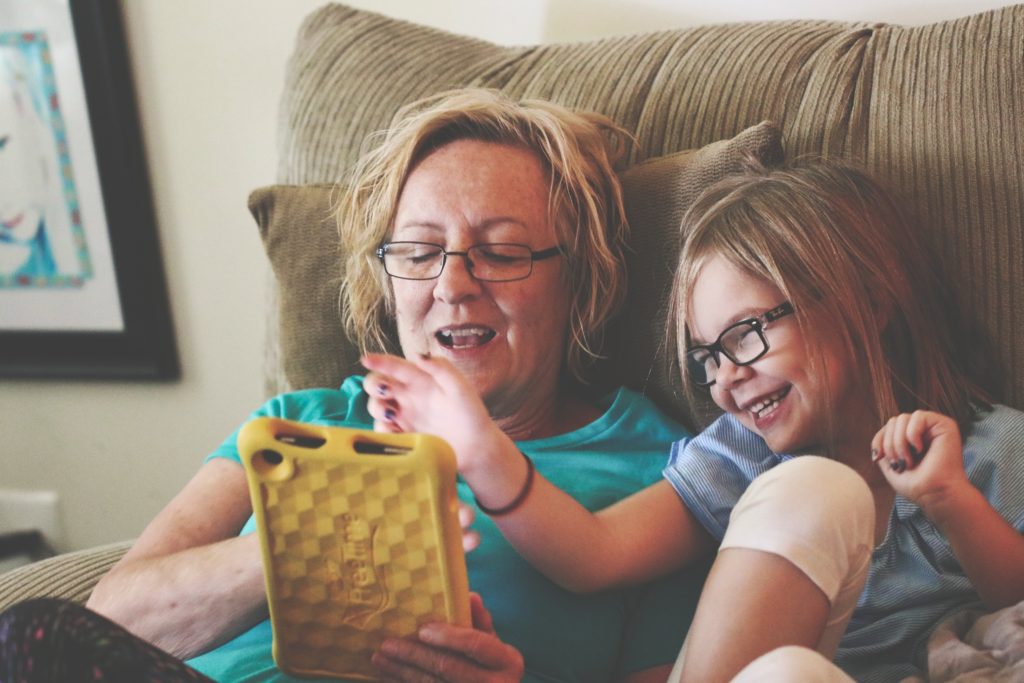 Mom and daughter laughing while looking at a yellow iPad.
