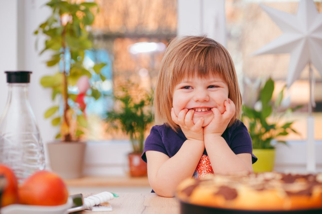 toddler sitting at kitchen table, smiling