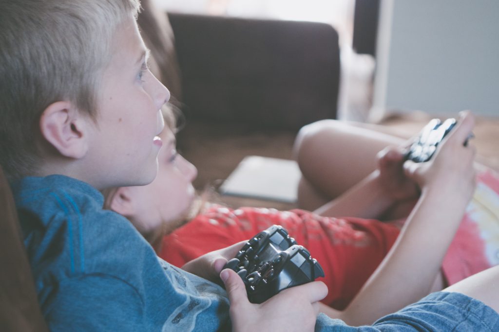 Boy and girl sit on couch holding video game controllers