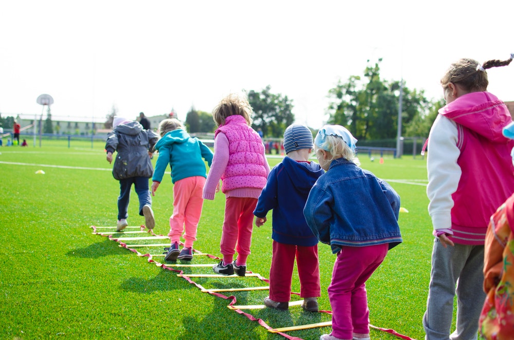 Children outside hopping through a rope ladder