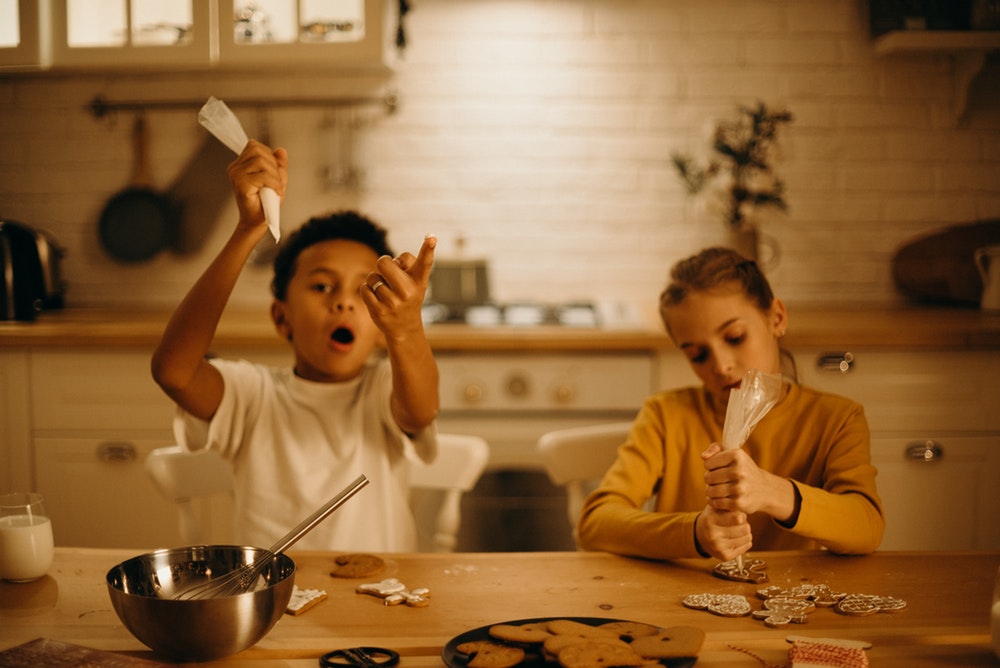 Two kids decorating gingerbread cookies