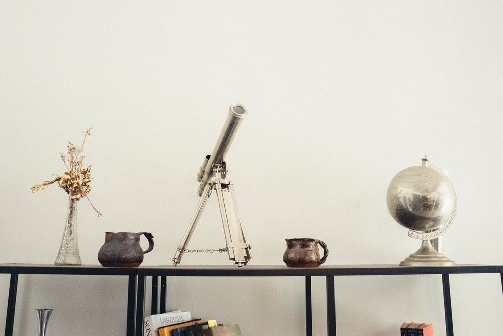 Silver telescope on desk next to globe