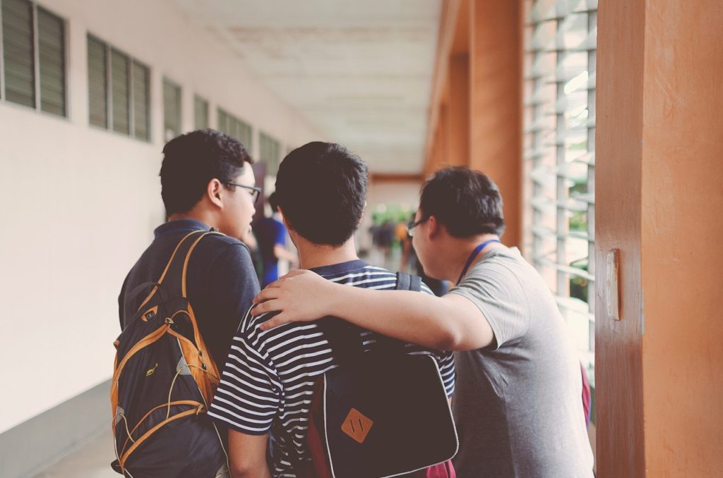 Group of friends walking down a hallway wearing backpacks