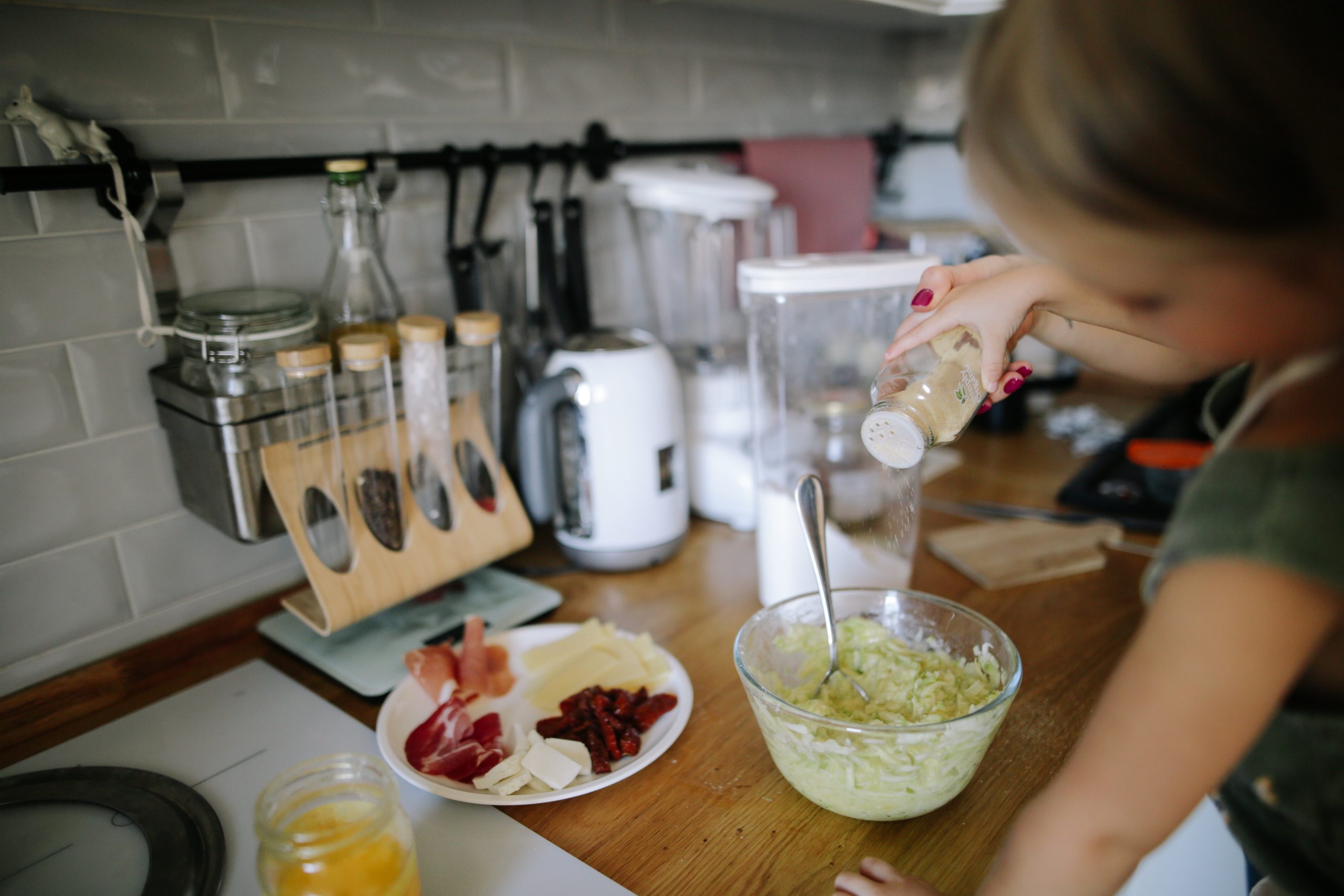 Child adding seasoning to egg salad