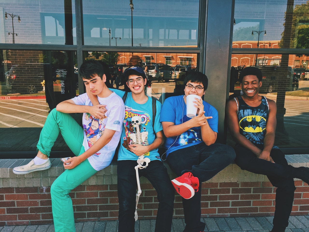 Four teenagers sitting on a ledge holding a science skeleton.