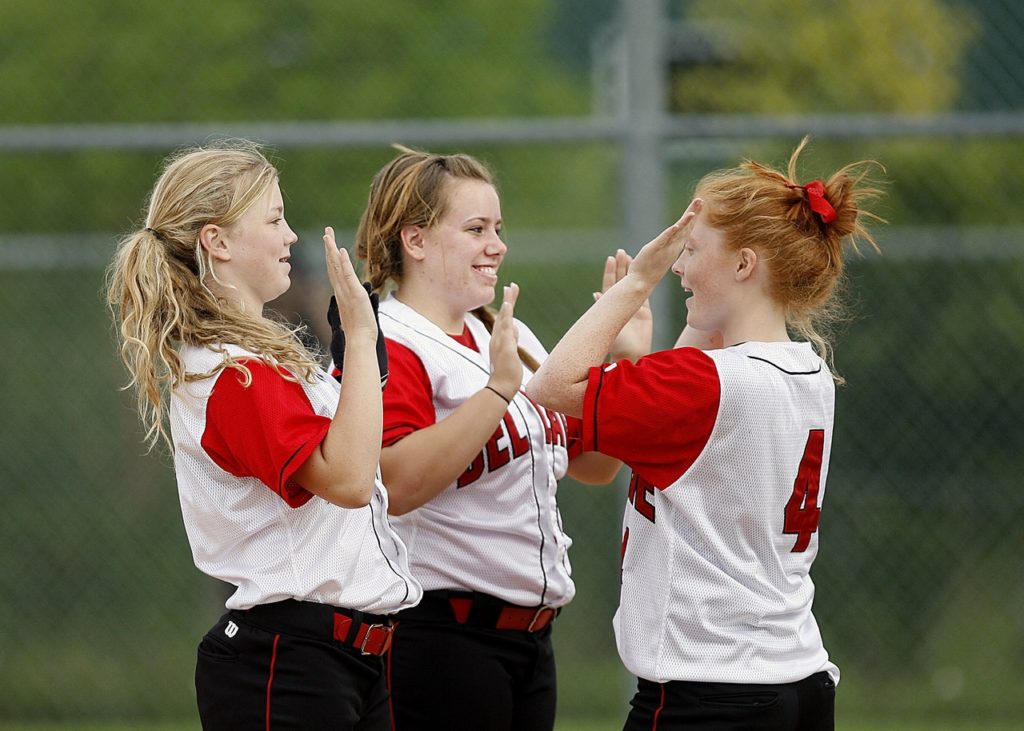 Three softball teammates high fiving