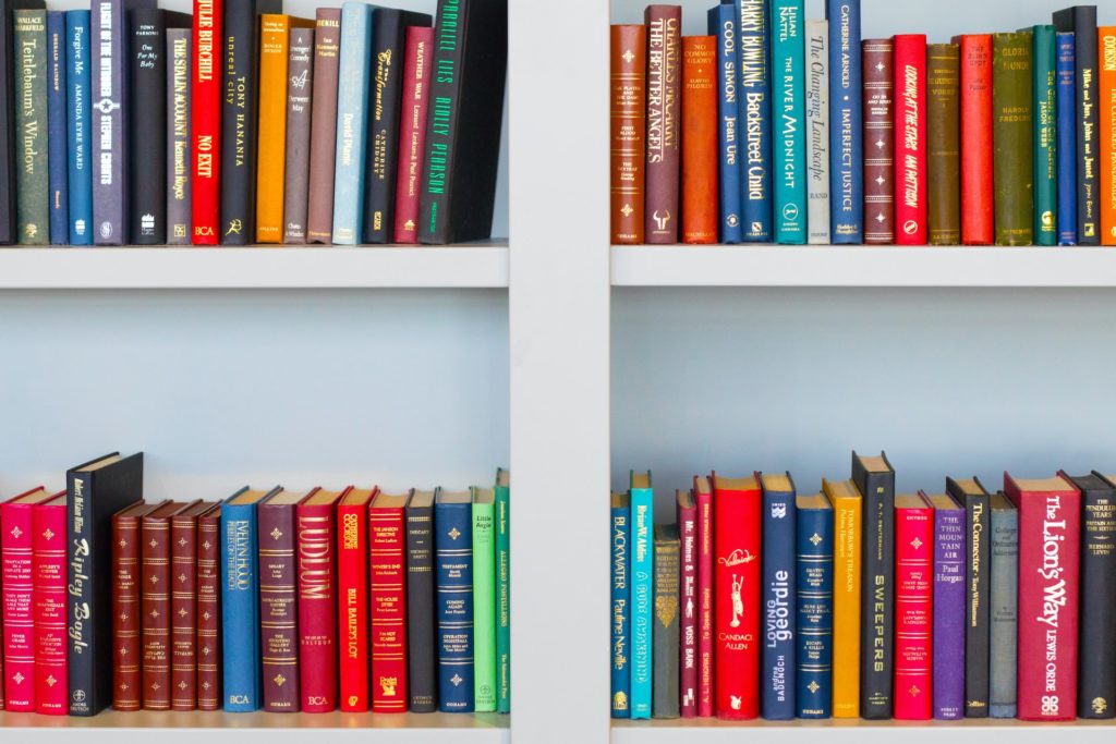 Colorful books on a white bookshelf.