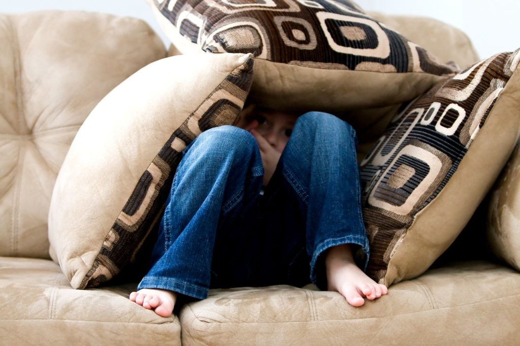 Boy hiding in pillows