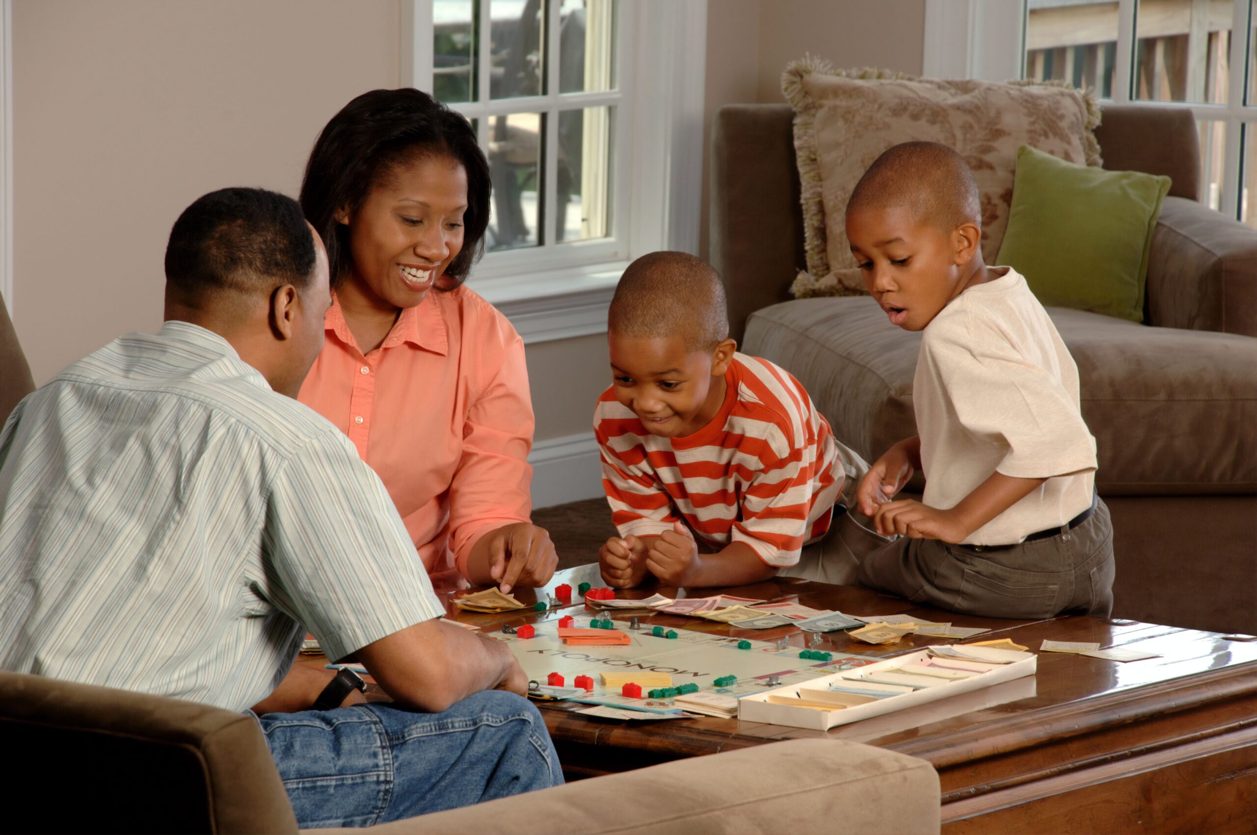 Family gathered playing Monopoly on coffee table
