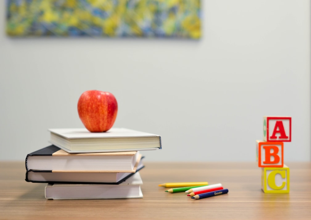 Stack of books, blocks, an apple and colored pencils