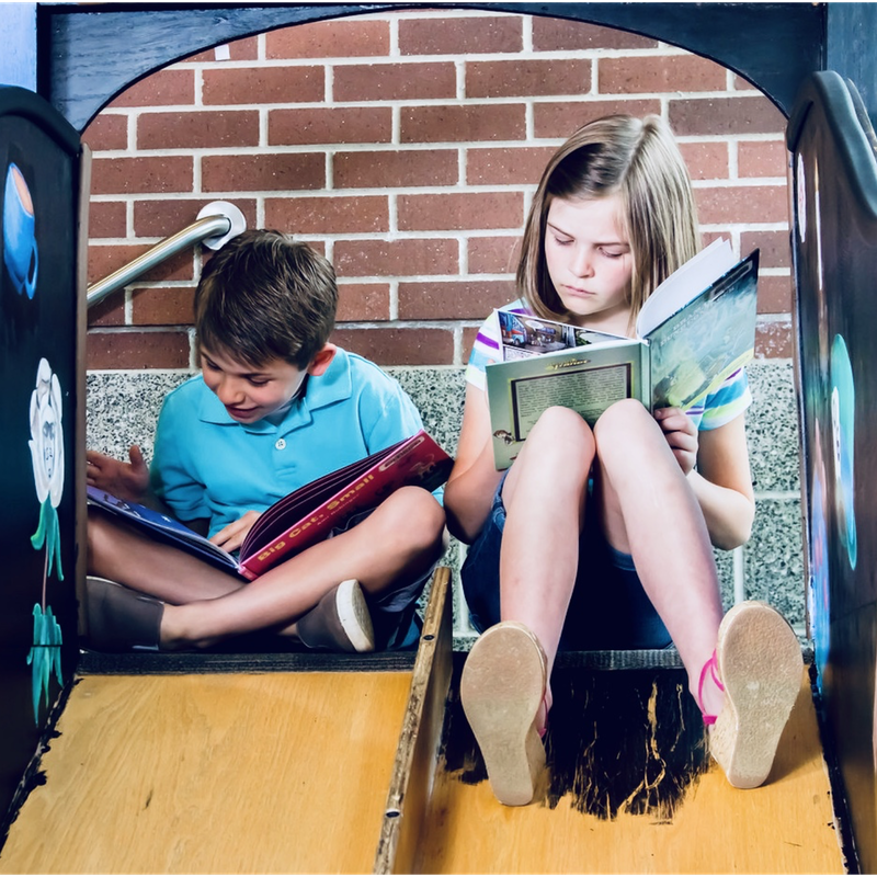 Two children reading atop steps outside