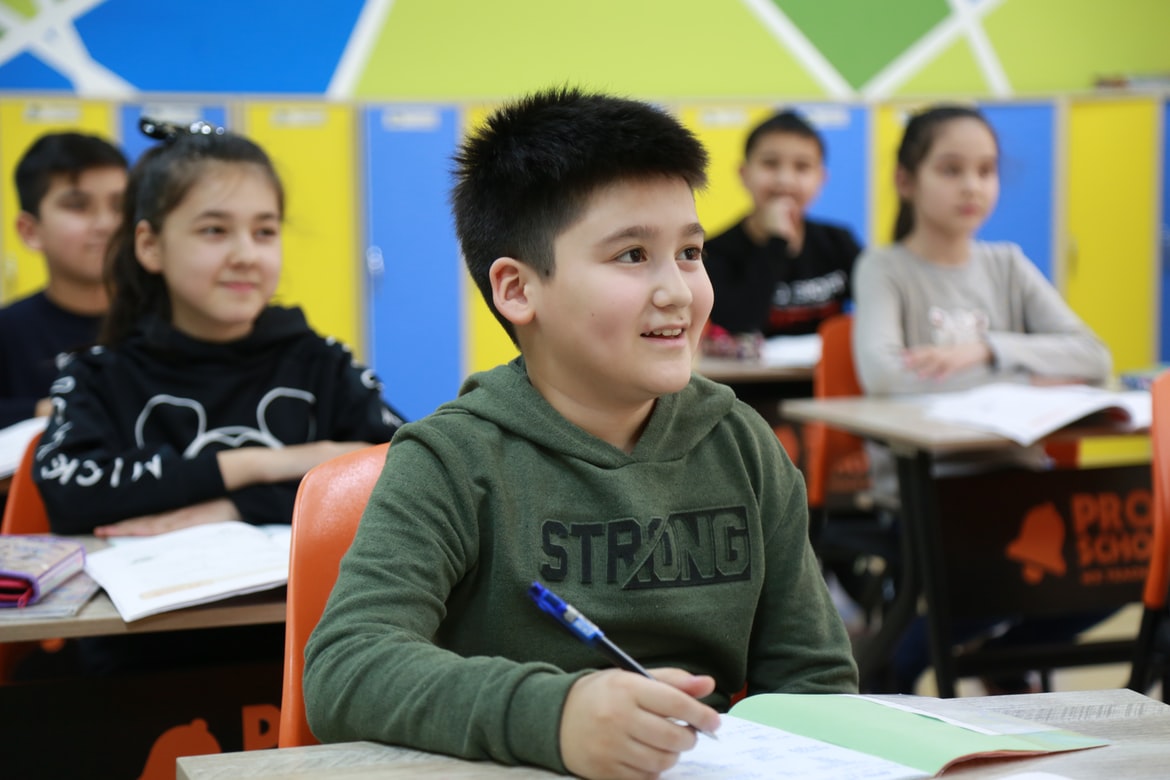 Row of younger children smiling in class