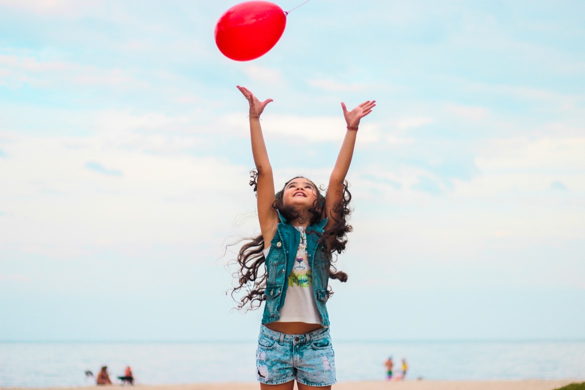 Child throwing balloon at beach