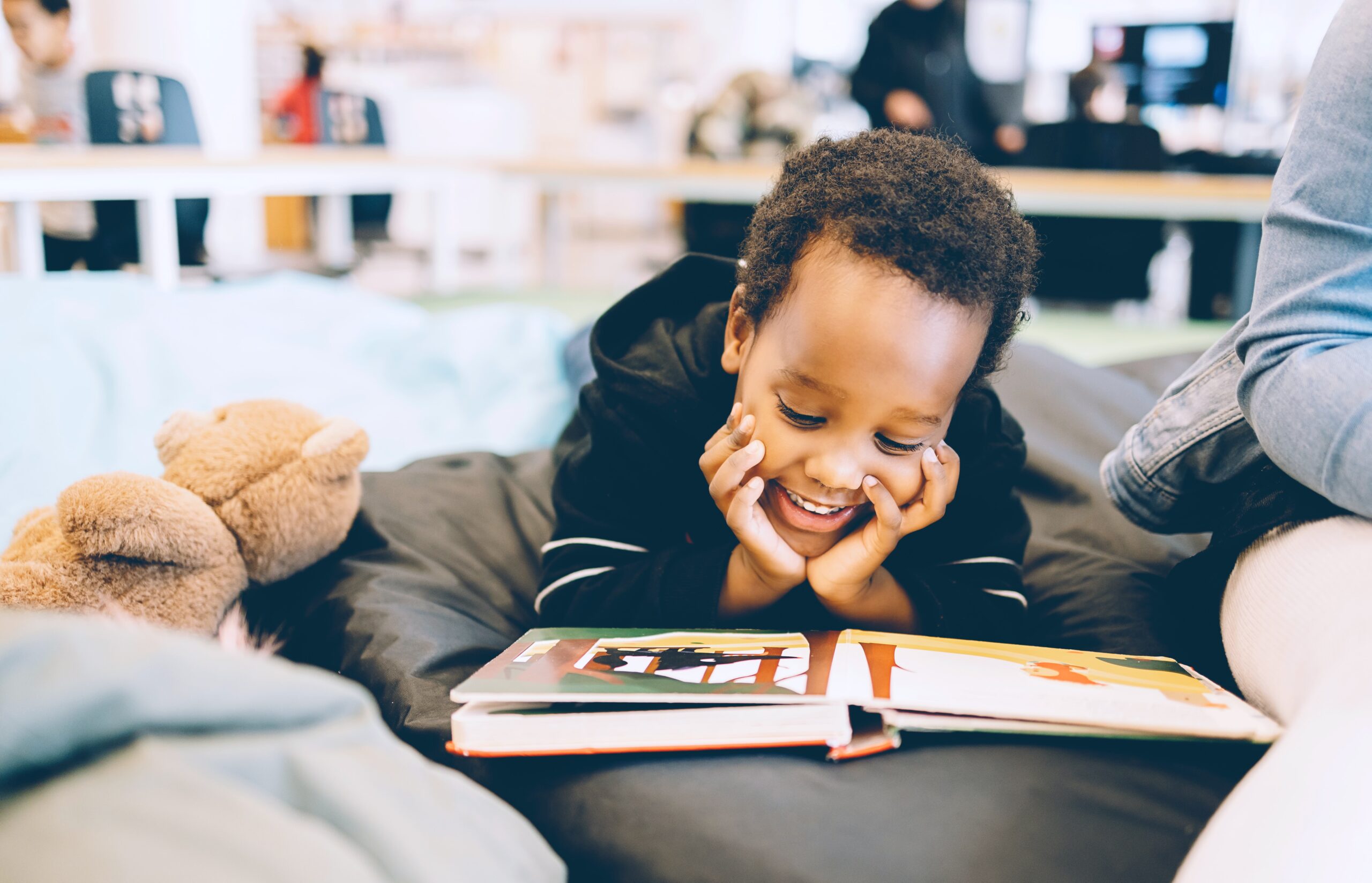 Child reading book with large smile